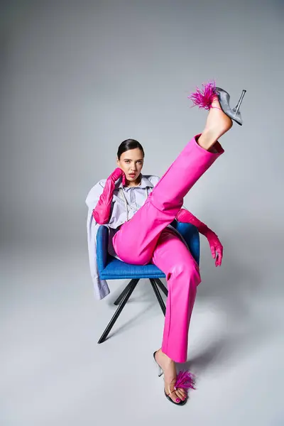 Chic bruna giovane donna in pantaloni rosa alla moda e scarpe sedute con la gamba sulla sedia — Foto stock