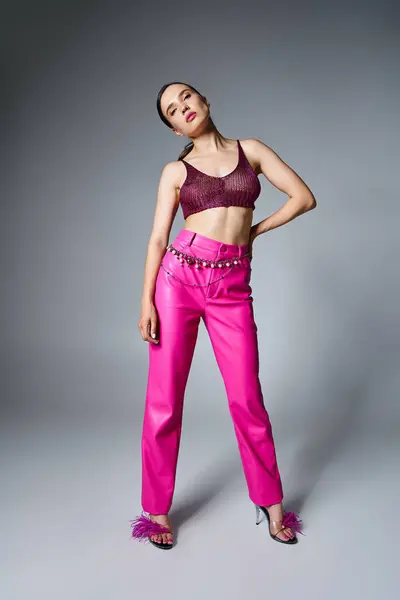Полная фотография модной брюнетки в трикотажном красном топе и кожаных брюках на сером фоне — стоковое фото
