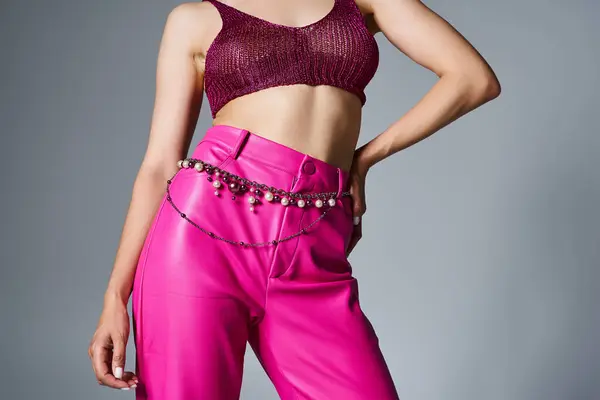 Cropped shot of woman wearing knitted bordeaux top and pink leather pants on grey background — Stock Photo