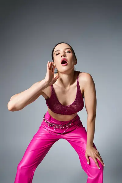 Selbstbewusste brünette Frau in trendiger pinkfarbener Hose und rotem Oberteil schreit vereinzelt in die Kamera — Stockfoto