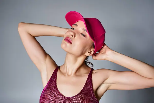 Donna sexy sognante in rosa top alla moda e cappuccio tenendosi per mano dietro la testa agghiacciante — Foto stock