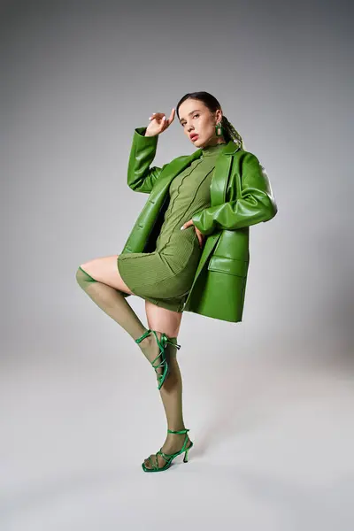 Foto completa de la mujer en mini vestido verde, chaqueta de cuero, calcetines de rodilla posando glamorosamente - foto de stock