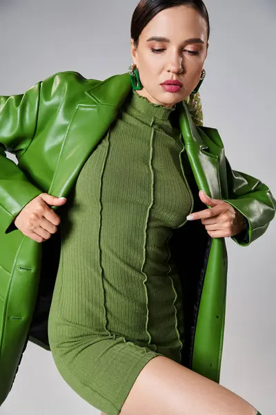 Stylish and brunette young woman in total green and trendy look holding her leather jacket — Stock Photo