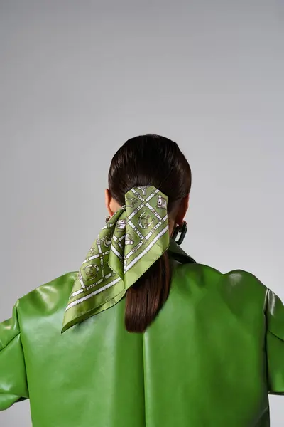 Rückansicht einer brünetten Frau mit grüner Lederjacke und Kopftuch im Studio — Stockfoto