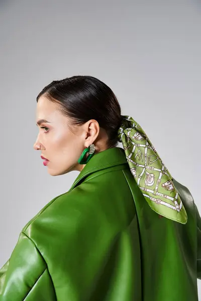Vista lateral de la mujer morena con aspecto verde de moda y la cabeza bufanda mirando hacia otro lado, ajuste de estudio - foto de stock