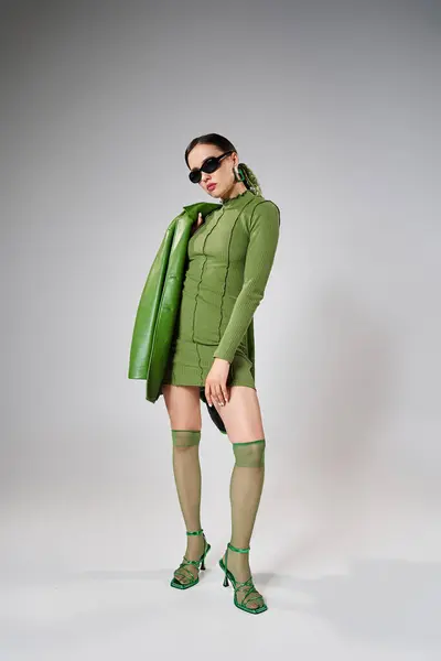 Fabuleuse fille en mini-robe verte, veste en cuir, chaussettes à genoux et chaussures, mains sur la cuisse — Photo de stock