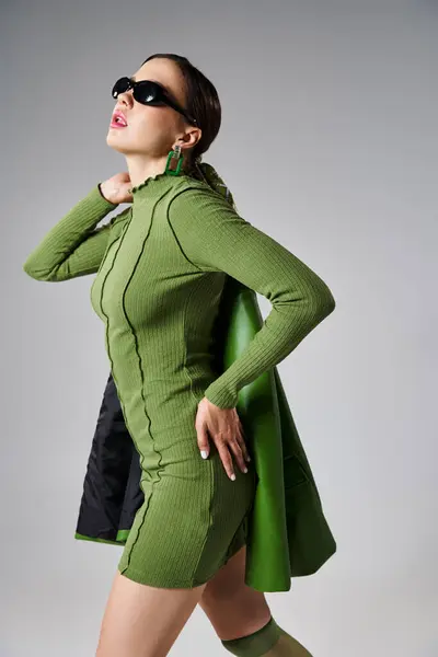Portrait of fancy brunette woman in total green trendy look and sunglasses touching her waist — Stock Photo