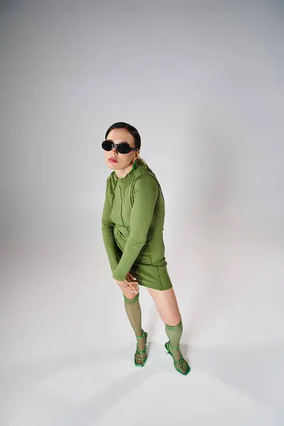 Vue du dessus de jolie femme au look vert total tendance, portant des lunettes noires sur fond gris — Photo de stock