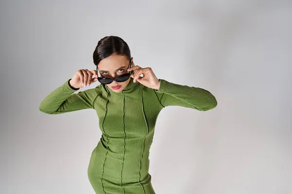 Top view of woman in green outfit, touching her eyewear with both hands and looking at camera — Stock Photo