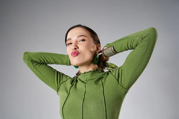 Portrait of fancy brunette woman in total green trendy look blowing kisses to camera on grey — Stock Photo