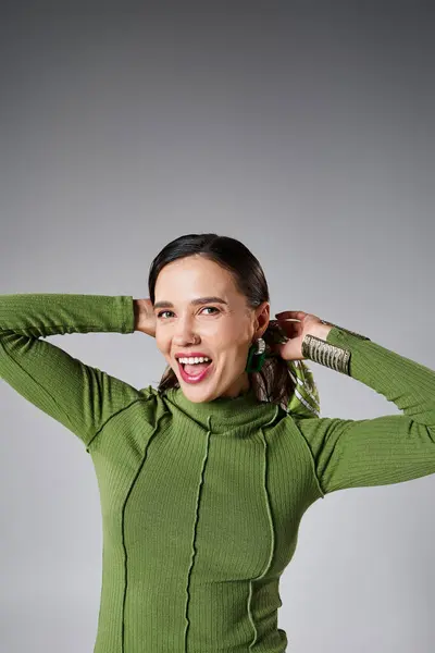 Porträt einer fröhlich lächelnden Frau im grünen trendigen Outfit, die isoliert auf grauem Hintergrund lacht — Stockfoto