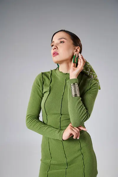 Ritratto di donna bruna che indossa total look verde alla moda, toccando i suoi orecchini — Foto stock
