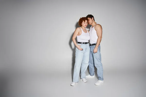 Appealing sexy couple in blue jeans posing together lovingly on gray background, relationship — Stock Photo