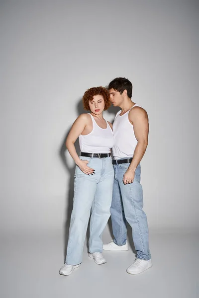 Appealing sexy couple in blue jeans posing together lovingly on gray background, relationship — Stock Photo
