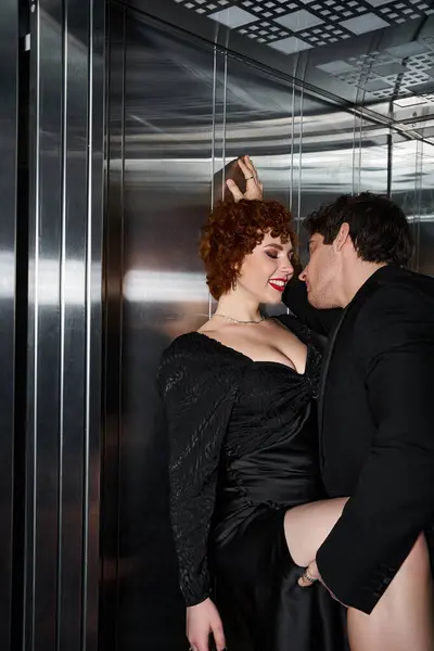 Cheerful loving boyfriend and girlfriend in elegant black attires hugging in elevator, sexy couple — Stock Photo