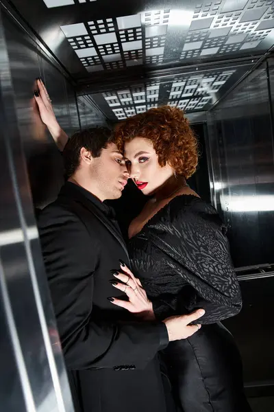 Sexy beautiful couple in chic black dress and suit hugging in elevator and looking at camera — Stock Photo