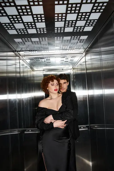 Tentant amour petit ami et petite amie dans élégant noir vêtements câlins dans l'ascenseur, couple sexy — Photo de stock