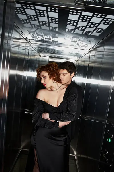 Sexy appealing couple in elegant black dress and suit hugging lovingly in elevator after date — Stock Photo