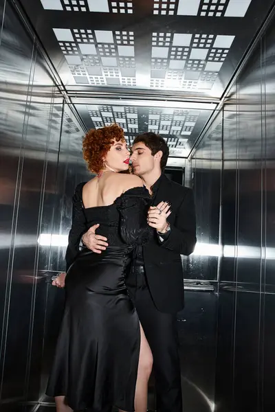 Sexy attractive couple in elegant black dress and suit hugging lovingly in elevator after date — Stock Photo