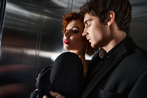 Engageant couple sexy en robe noire élégante et costume étreignant amoureusement dans l'ascenseur après la date — Photo de stock