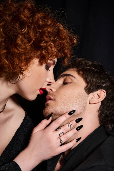 Atractivo novio y novia en traje elegante besándose apasionadamente en el fondo negro, pareja - foto de stock