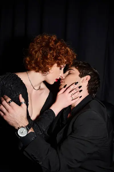 Appealing boyfriend and girlfriend in chic attire kissing passionately on black backdrop, couple — Stock Photo