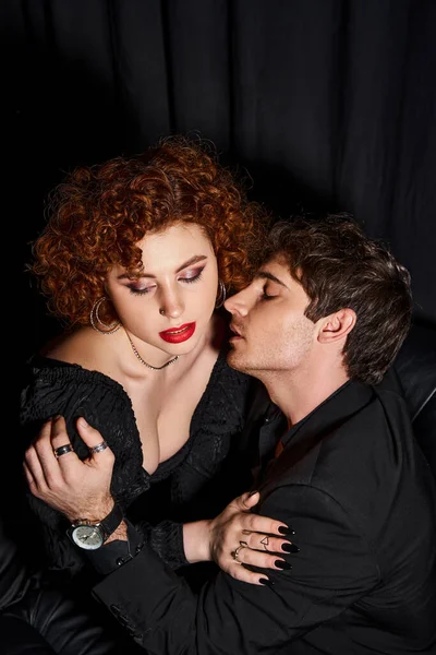 Atractivo novio y novia en elegante traje besándose apasionadamente en negro telón de fondo, sexy pareja - foto de stock