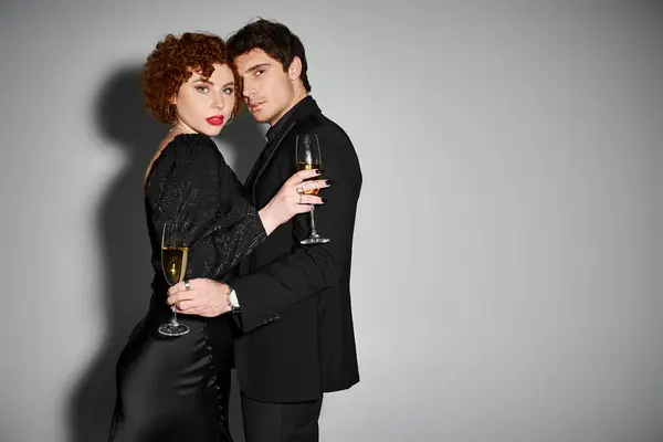 Sexy bella coppia in abito nero abbracciare e guardando la fotocamera con champagne in mano — Foto stock