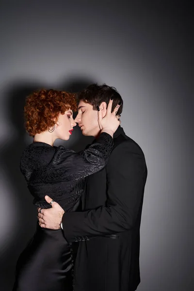 Reizvolles sexy Paar in schwarzen eleganten Kleidern bereitet sich darauf vor, einander vor grauem Hintergrund zu küssen — Stockfoto