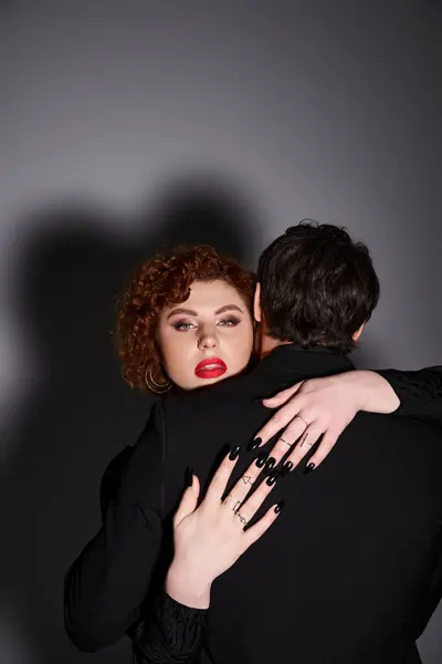 Vista posteriore di uomo in abito nero abbracciando calorosamente la sua ragazza che guardando la fotocamera, coppia sexy — Foto stock