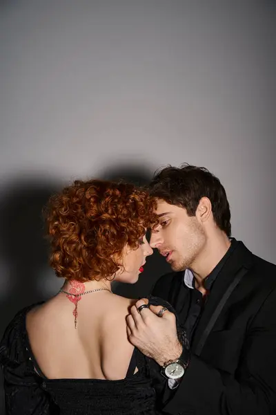 Atraente sexy casal em preto elegante trajes beijando e abraçando amorosamente no fundo cinza — Fotografia de Stock