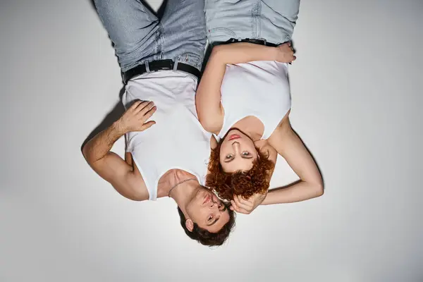 Verführerischer Mann und Frau in blauen Jeans, die zusammen auf dem Boden liegen und in die Kamera schauen, sexy Paar — Stockfoto
