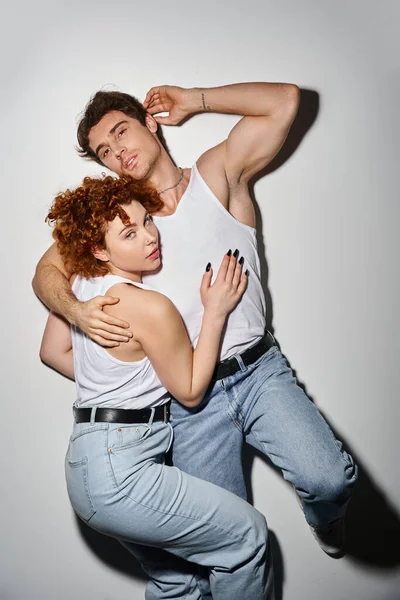 Appealing man and woman in blue jeans lying on floor together and looking at camera, sexy couple — Stock Photo