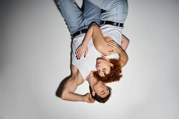 Beautiful woman in jeans lying on floor next to her boyfriend and looking at camera, sexy couple — Stock Photo