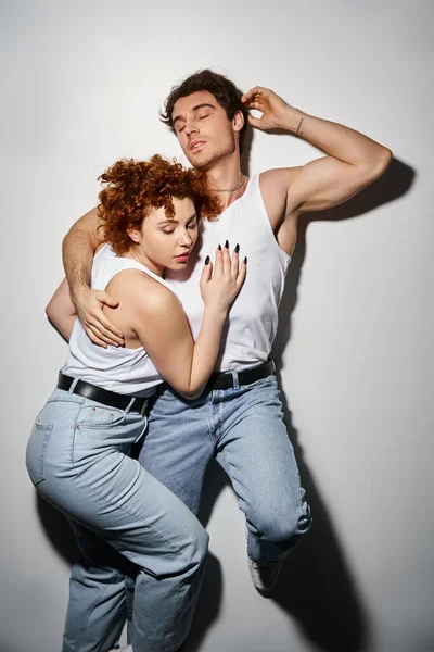 Good looking alluring couple in casual blue jeans lying on floor together and hugging warmly — Stock Photo