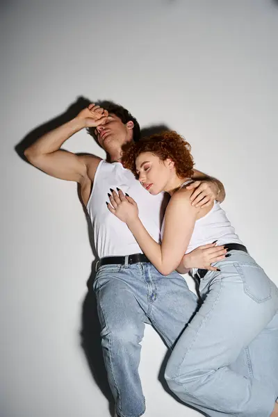 Boa aparência casal sedutor em jeans azuis casuais deitado no chão juntos e abraçando calorosamente — Fotografia de Stock