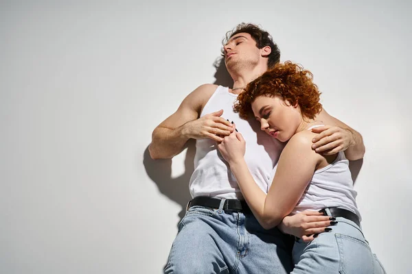 Good looking alluring couple in casual blue jeans lying on floor together and hugging warmly — Stock Photo