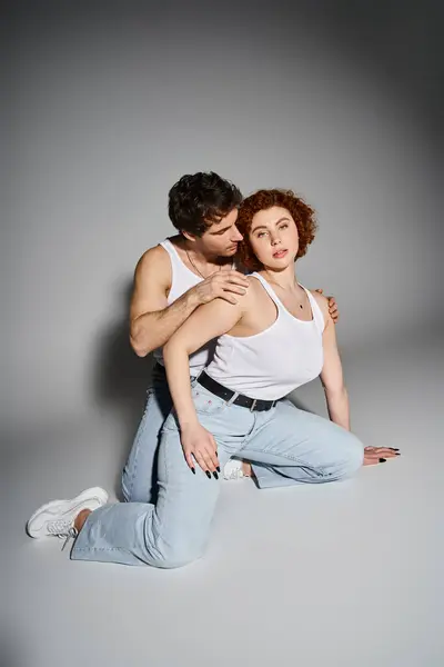 Atractiva joven sentada en el suelo junto a su novio y mirando a la cámara, sexy pareja - foto de stock