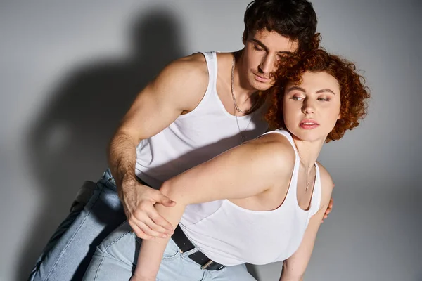 Attraktive Mann und Frau in blauen Jeans sitzen zusammen auf dem Boden und umarmen sich herzlich, sexy Paar — Stockfoto