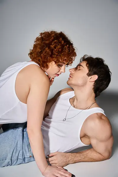 Beautiful sexy couple in cozy blue jeans reclining on floor together preparing to kiss lovingly — Stock Photo