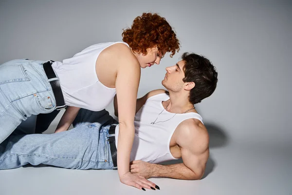 Good looking sexy couple in casual attire preparing to kiss passionately on gray background — Stock Photo