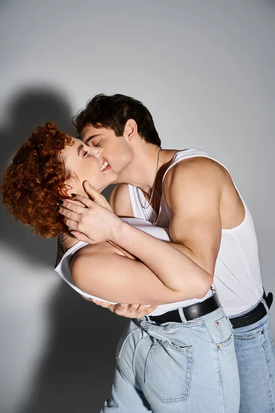 Handsome man in cozy jeans hugging and kissing his cheerful beautiful girlfriend, sexy couple — Stock Photo