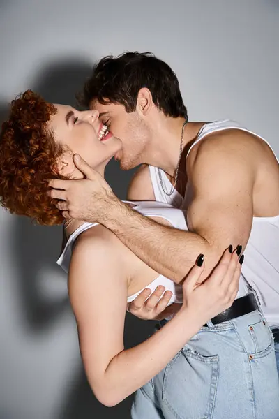Schöner Mann in gemütlichen Jeans umarmt und küsst seine fröhlich schöne Freundin, sexy Paar — Stockfoto