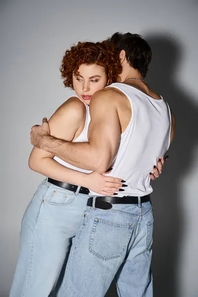 Atractivo novio y novia en traje casual abrazándose amorosamente en el fondo gris, sexy pareja - foto de stock