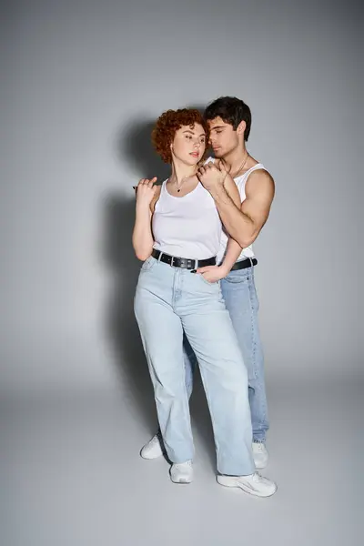 Charming boyfriend and girlfriend in casual attire hugging lovingly on gray backdrop, sexy couple — Stock Photo
