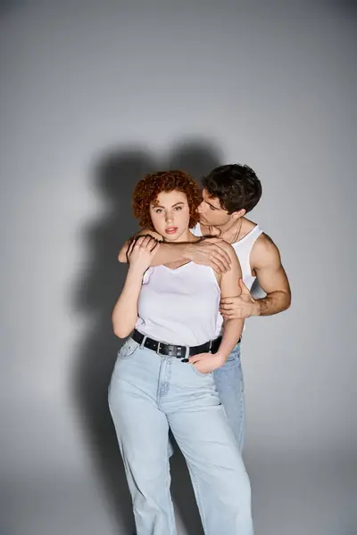 Attractive man in jeans hugging his beautiful girlfriend while she looking at camera, sexy couple — Stock Photo