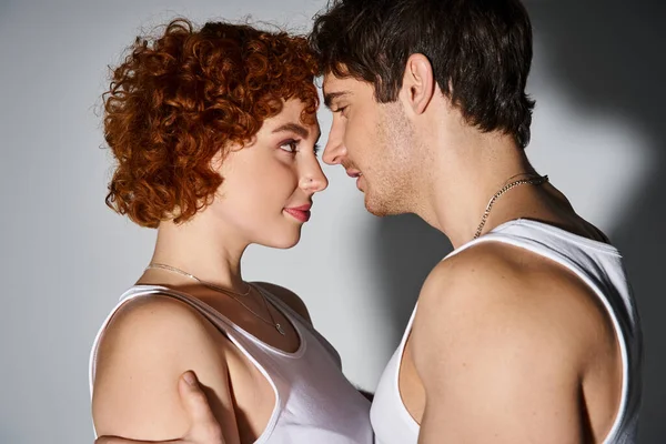 Tempting boyfriend and girlfriend in casual attire hugging lovingly on gray backdrop, sexy couple — Stock Photo