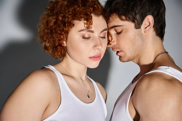 Engaging boyfriend and girlfriend in casual attire hugging lovingly on gray backdrop, sexy couple — Stock Photo