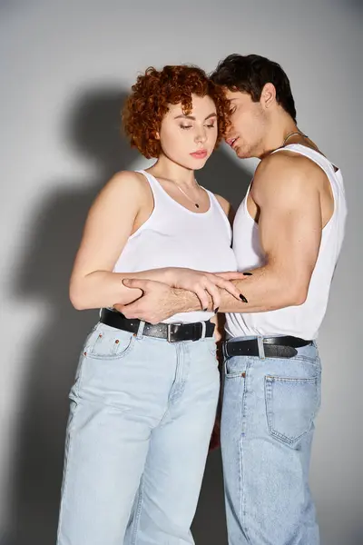 Engaging boyfriend and girlfriend in casual attire hugging lovingly on gray backdrop, sexy couple — Stock Photo