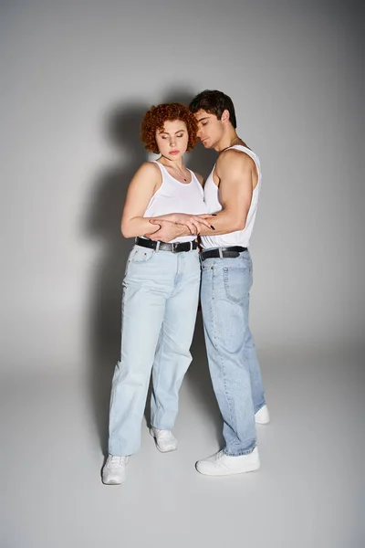 Beautiful boyfriend and girlfriend in casual attire hugging lovingly on gray backdrop, sexy couple — Stock Photo